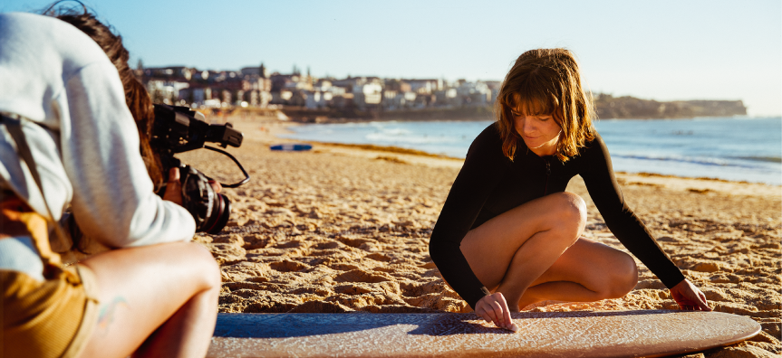 woman putting wax on a surfboard