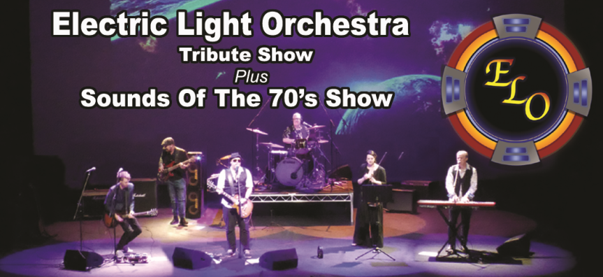The Electric Light Orchestra Tribute Band pictured on a stage - there are two men playing guitar and a third playing bass, a man on the drums and one on the keyboard and a woman who has a mic and music stand in front of her. They look energetic!