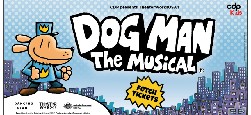 A cartoon image of a Dog Man dressed as a policeman in the foreground. He is standing on a white hill. In the background is a cartoon city. Dog Man looks ready for action!