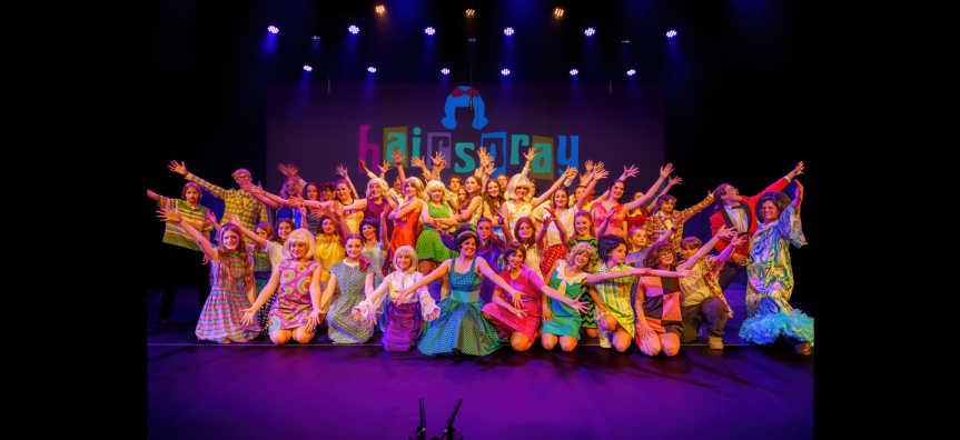 Performing arts students pose joyfully on stage