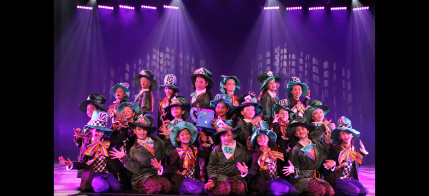 A group of young people in Mad Hatter costumes posing at the end of a dance