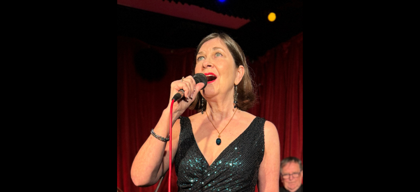 Meredith O'Reilly singing on stage in a beautiful green dress