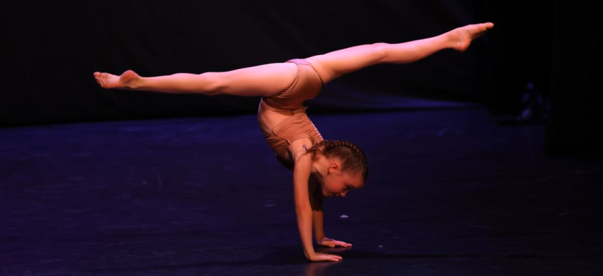 A young girl is doing a handstand on stage 