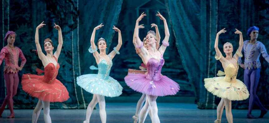 Four ballerinas pose on stage in colourful costumes. 