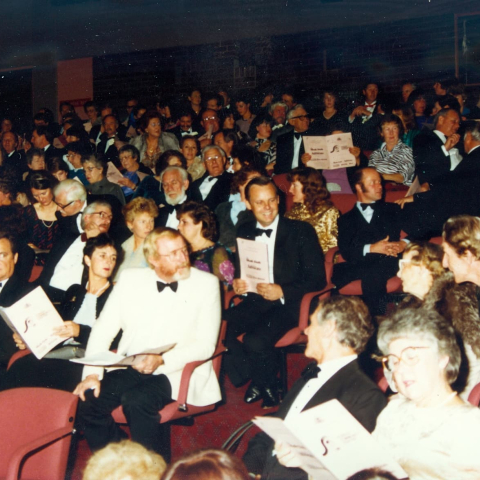 A picture of a theatre audience engaged in conversation. It's 1985 and it looks it!